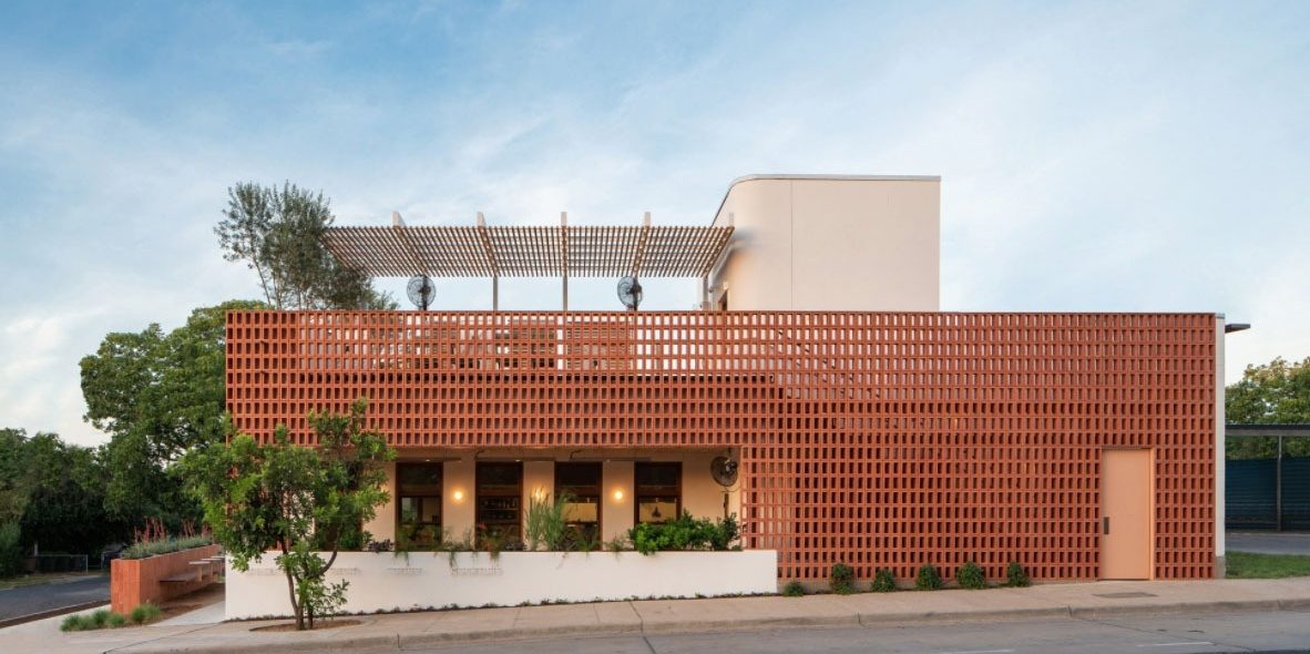 Paperboy restaurant in Austin, Texas: a D'Hanis terra cotta screen tile wall wrapping the two-story building in afternoon light