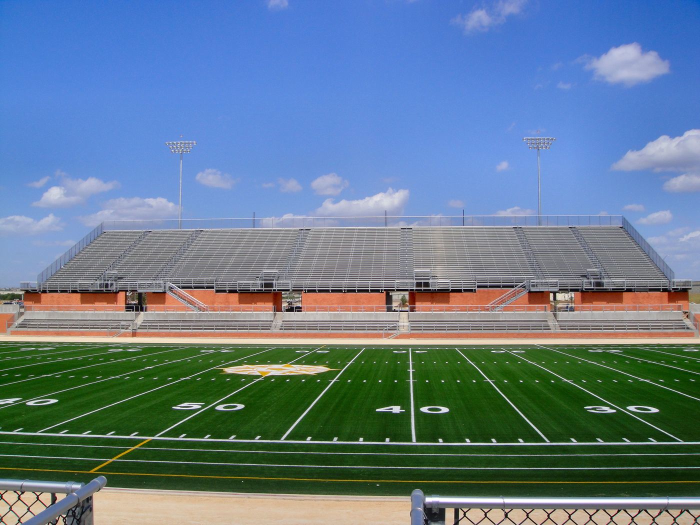 Heroes Stadium in San Antonio, Texas: D'Hanis terra cotta brick walls beneath the grandstand, with the green football field in front and blue sky above